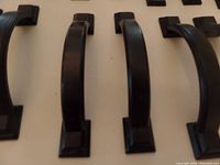 Close-up side angle view of three black matte arched square cabinet pulls showing design and finish.