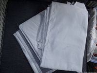 Two folded white curtain liner panels showing the front white side, laid out on dark surface.