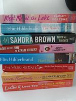 Side view of spines of 8 paperback romance novels stacked horizontally showing titles and authors.