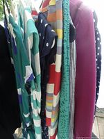 Side view of hanging clothing items showing variety of colors and textures including stripes, polka dots, ribbed fabric, and eyelet lace
