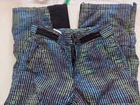 Snow pants folded showing front pockets and waistband with surrounding pattern.