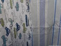 Fabric piece with print of various vintage vehicles in blue, green, yellow on cream background, includes cars, trucks, motorbike
