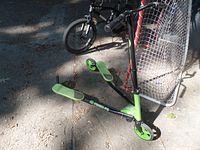 Fliker drift scooter, green and black, parked next to a hockey net and a bike. Shows the scooter's overall condition.