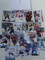 Photo showing approx. 20 assorted hockey cards laid out on white surface with a paper numbered '1'