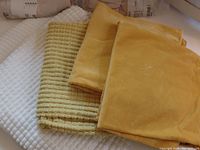 Photo of stacked pillow covers showing yellow fuzzy, yellow cotton velvet, and off-white fuzzy textures.