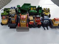 Front view of 13 diecast kids' vehicles including Disney Planes-themed characters with eyes and numbers, construction vehicles, and green tractors