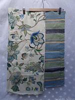 Two pieces of fabric hanging side-by-side; one with a green/blue striped pattern, the other with floral Kaufmann fabric.
