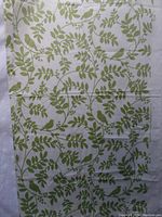 Photo showing full layout of the fabric piece with green leafy branches and birds on white background