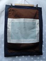 Single silk pillow sham hanging showing front pattern in light blue, white, brown and navy