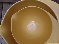 Close-up image of the inside of one yellow mixing bowl showing mild wear and scratches