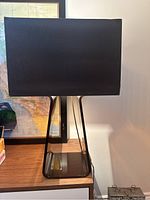 Front view of the lamp on a wooden surface showing the smokey acrylic base and chocolate brown fabric lampshade.