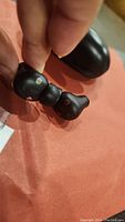 Close-up of black in-ear wireless earbuds held by hand showing left and right earbuds with 'b' logo and silicone ear tips.