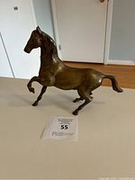 Bronze horse sculpture showing right side profile, with auction lot card 55 visible.