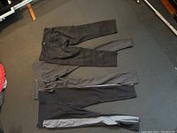Three pairs of Lululemon yoga pants laid flat showing front sides in black and grey color schemes.