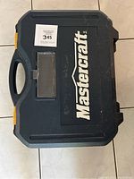 Closed black plastic carrying case with Mastercraft logo on the top.