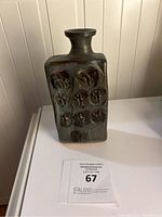 Front view of chimney vase showing rectangular shape with neck and impressed round motifs on surface.