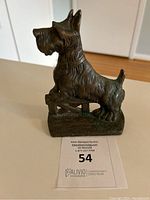Front angled view of the Scottish Terrier cast iron door stop on floor with auction card.