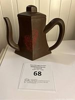 Rectangular Yixing teapot from front side showing handle, spout and red calligraphy decoration.