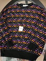 Full front view of the men's knit sweater showing multicolored geometric pattern and ribbed cuffs and hem.