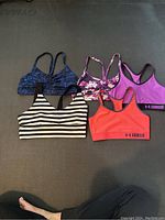 Top view of five short exercise tops, showing patterns and colors.