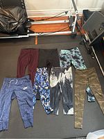 All seven pairs of workout pants laid out side by side showing variety of colors and prints