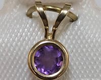 Close-up of the round faceted amethyst stone set in 14K gold bezel with split bail