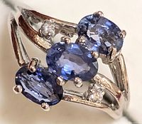 Front view showing three oval blue sapphires and two small round diamonds in split shank setting