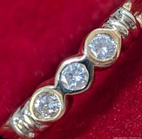 Front view showing three round brilliant diamonds in bezel-style settings