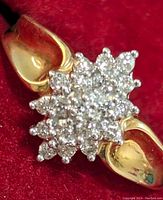 Angled top view of diamond cluster and yellow gold shanks on red background