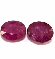 Close-up photo of two oval faceted ruby gemstones showing surface facet cuts and internal inclusions.