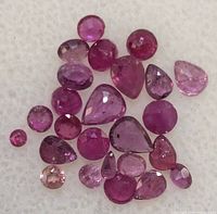 Close-up of various sized and shaped faceted ruby gemstones on white background