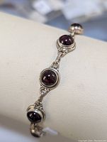 Close-up showing three round garnet cabochons set in silver bezels of the bracelet; highlighting stone color and metal finish.