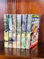 Seven vintage boys adventure novels standing upright, showing spines with titles and authors from Tom Corbett Space Cadet and Ken Holt Mystery series.