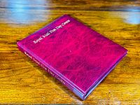 Closed red album titled 'Royal Mail First Day Covers' displayed on wooden surface.