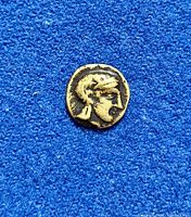 Front view of the coin showing profile of a human head wearing a helmet or headpiece on a blue background.