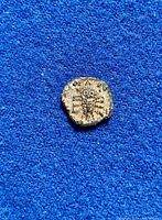 Front view of ancient coin on blue background showing engraved figure.