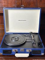 Front view of the open blue Crosley Cruiser turntable showing the black platter, tonearm, and interior lid with Crosley logo