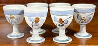 Six Frederika Ernsten signed stoneware goblets showing hand-painted floral decoration and pale blue glaze accents.