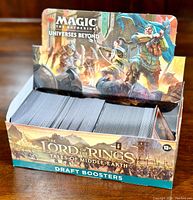 Full box of Magic: The Gathering draft booster cards with The Lord of the Rings artwork visible on packaging.