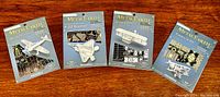 Four unopened Metal Earth 3D laser cut plane model kits laid out on a wooden surface showing the front packaging for Mitsubishi Zero, F-22 Raptor, a generic biplane, and Polaris VI