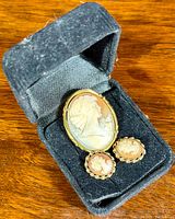 Photo of cameo brooch/pendant and matching earrings displayed inside black jewelry box.