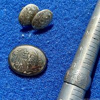 Photo of sterling silver oval etched floral earrings, brooch, and ring on blue background with ring on mandrel showing size 8 measurement.