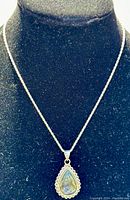 Full view of the vintage sterling silver chain and pear-shaped labradorite pendant displayed on black velvet stand.