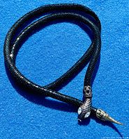 Full length of black mesh snake belt coiled on blue background.