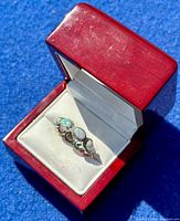 Ring in red jewelry box showing three fire opal cabochons and CZ stones.