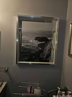 Framed black and white coastal landscape photo hanging on indoor wall