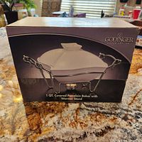 Front view of the product box showing the product image and brand Godinger, indicating a 1 quart covered porcelain baker with warmer stand.
