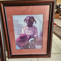 Full view of the framed art print showing a child holding a wide brim hat, with matting and dark wood frame.