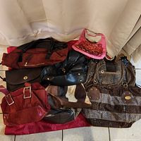 Overview of 8 vintage purses and handbags arranged on floor with white fabric background, showing variety in colors, materials, and sizes.