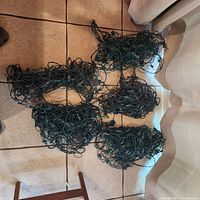 Five bundles of green net Christmas lights laid on floor, all cables bundled tightly for storage.